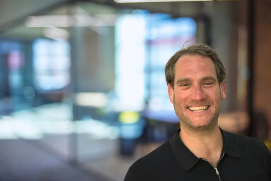 A smiling man wearing a black collared shirt.
